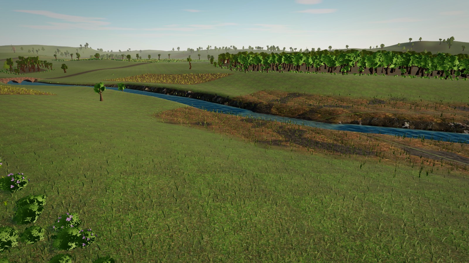 Arroyo entre pradera y una orilla de barro y carrizo, con un bosque denso al fondo.
